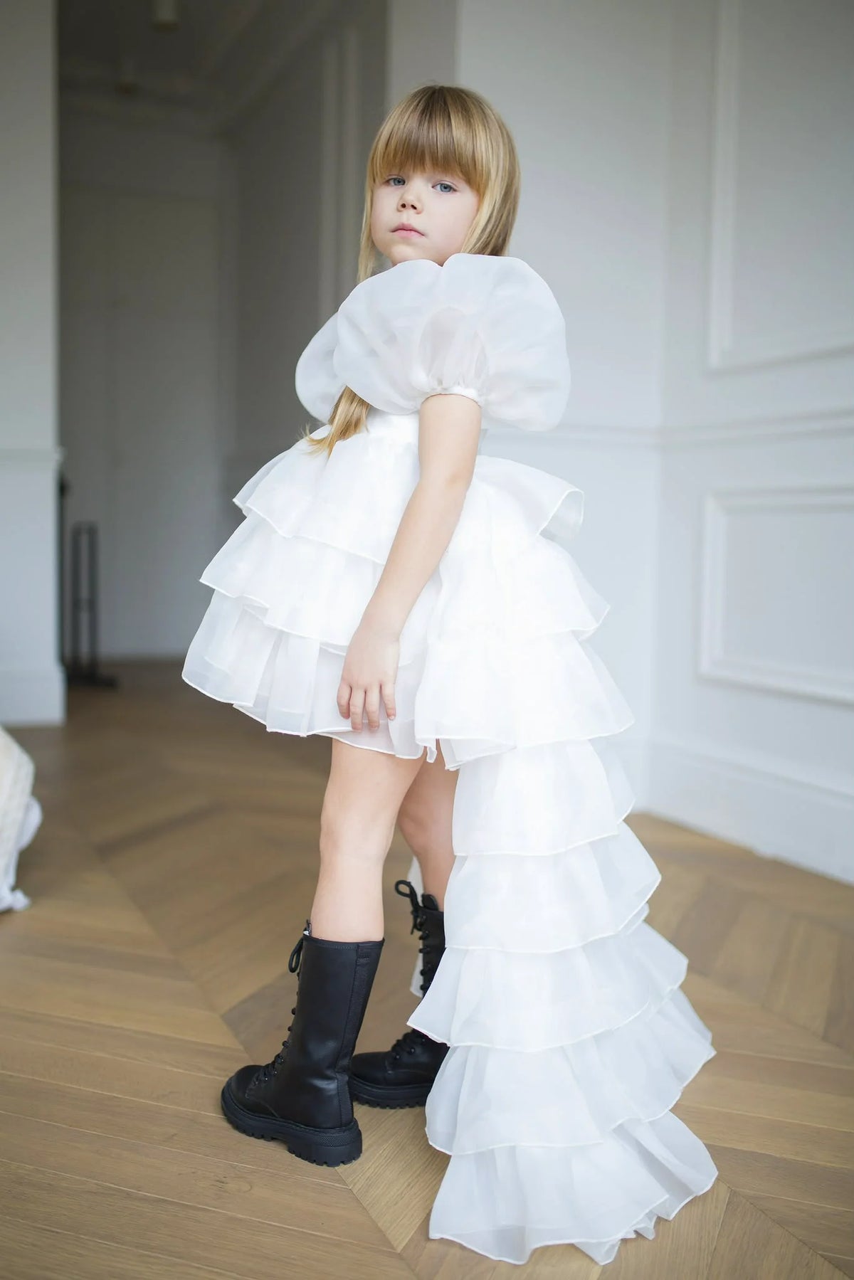 Enfant portant une robe blanche à volants et à traîne dans un intérieur lumineux Image