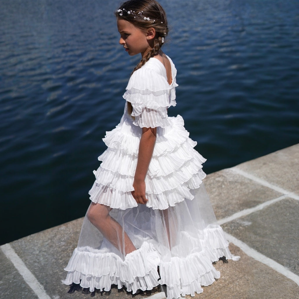 Jeune fille portant une robe blanche à volants avec traîne en tulle, ambiance marine chic.